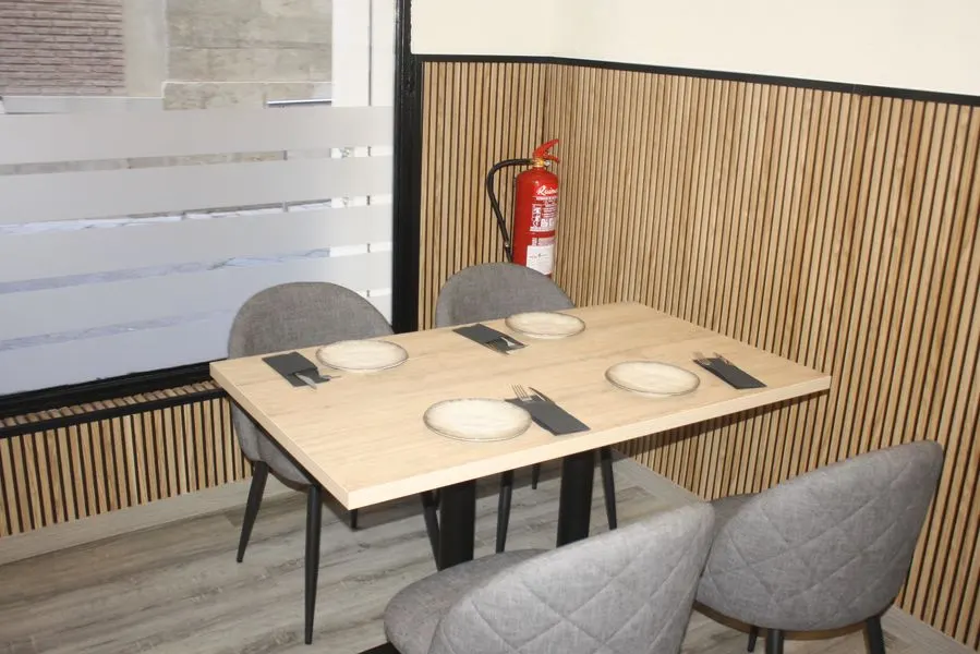Mesa para cuatro preparada junto a la pared de listones de madera de El Salón de San Lorenzo